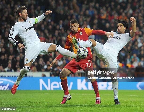 Burak Yilmaz of Galatasaray is challenged by Sergio Ramos and Sami Khedira of Real Madrid during the UEFA Champions League Quarter Final first leg...