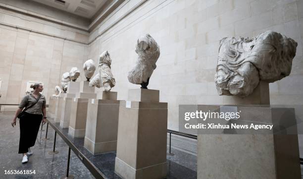 Woman views the Parthenon Marbles, a collection of stone objects, inscriptions and sculptures, also known as the Elgin Marbles, in the British Museum...
