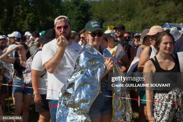 People protect themselves from the heat under the survival blanket as they attend the concert of the US American pop-rock band Imagine Dragons at the...