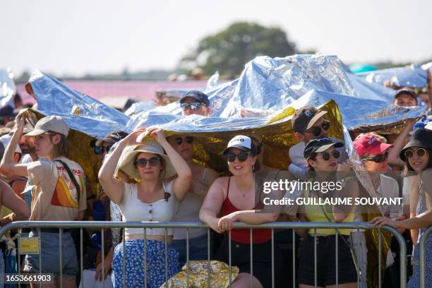 People protect themselves from the heat under the survival blanket as they attend the concert of the US American pop-rock band Imagine Dragons at the...