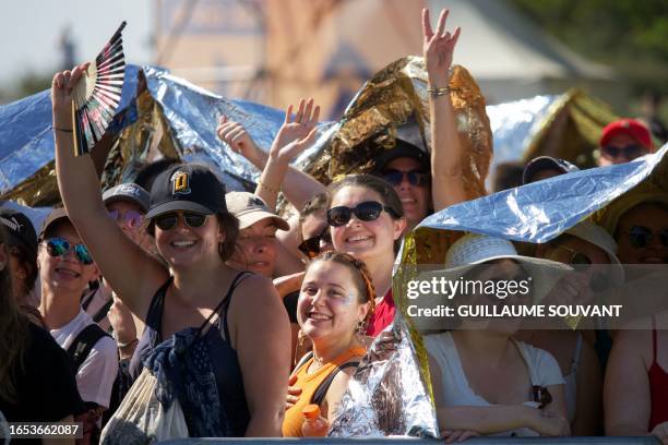 People protect themselves from the heat under the survival blanket as they attend the concert of the US American pop-rock band Imagine Dragons at the...