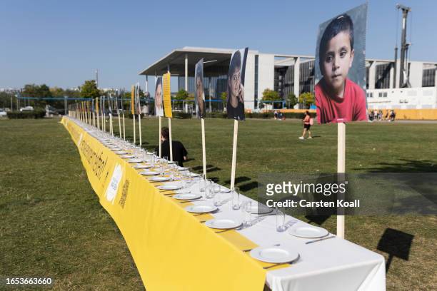 Dinner table 50 meters long showing portraits of orphans stands set in front of the Reichstag in a charity push called "Meals for Orphans" to benefit...