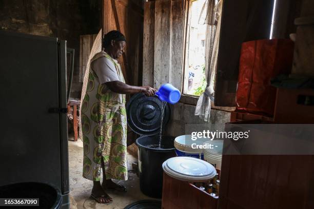 Woman pours water into a bucket in her house in Bellevue 2, in Libreville on September 8, 2023.