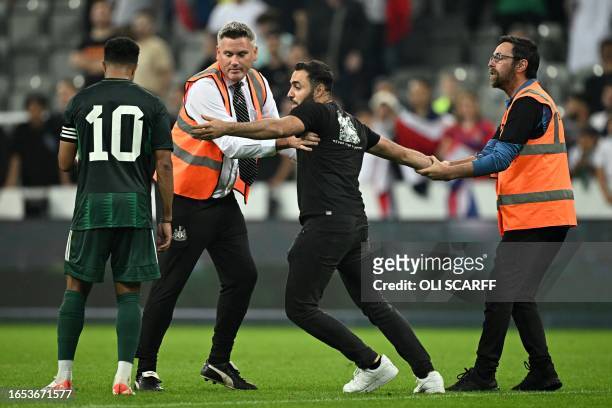 Stewards stop a pitch invader who wanted to take a selfie with Saudi Arabia's midfielder Salem al-Dawsari during the international friendly football...