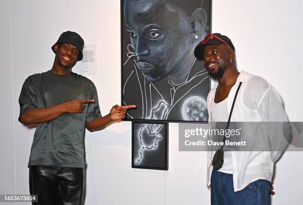 Micheal Ward poses in front of a portrait of himself with artist Hamed Maiye at a portrait the opening night of Netflix's "Portrait Of A Top Boy"...