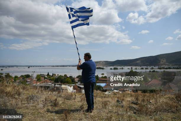 Man stands with the Greek flag as the Pineiada Village is submerged after the heavy flood in Thessaly, Greece on September 08, 2023.