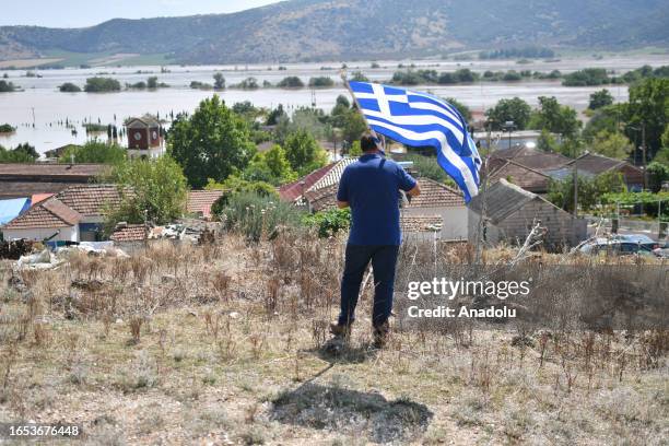 Man stands with the Greek flag as the Pineiada Village is submerged after the heavy flood in Thessaly, Greece on September 08, 2023.