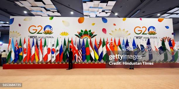 Indian volunteer arranges the participating country's flags at International Media Centre near the Bharat Mandapam on September 8, 2023 in New Delhi,...