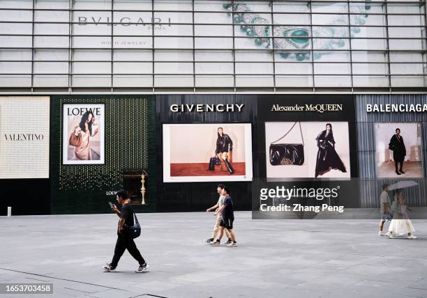 Pedestrians walk past huge billboards of luxury brands on the street in the city center. According to Morgan Stanley, with China lifting its...