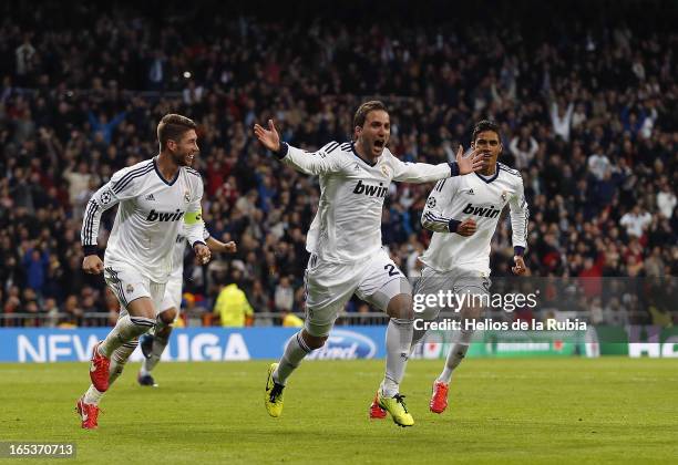 Gonzalo Higuain of Real Madrid celebrates with team-mates Sergio Ramos and Raphael Varane after scoring their team's third goal during the UEFA...