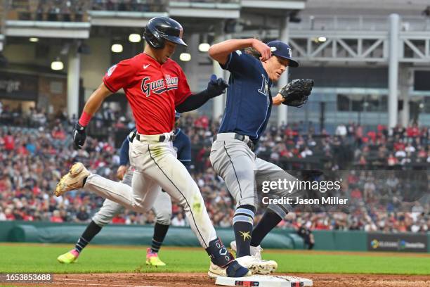 Steven Kwan of the Cleveland Guardians is safe at first as starting pitcher Tyler Glasnow of the Tampa Bay Rays tries to beat him to first base on a...