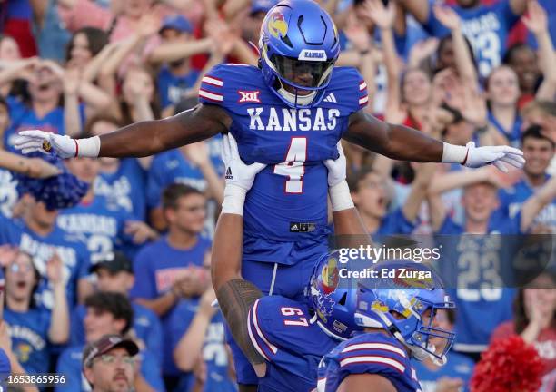 Running back Devin Neal of the Kansas Jayhawks is lifted into the air by offensive lineman Dominick Puni after scoring a touchdown in the first half...