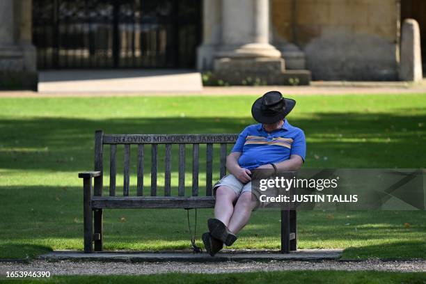 Man sleeps on a bench in front of the Wren Library, part of Trinity College, in Cambridge, north of London on September 9 as the late summer heatwave...