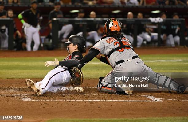 Corbin Carroll of the Arizona Diamondbacks is tagged out at home by Adley Rutschman of the Baltimore Orioles during the fourth inning at Chase Field...
