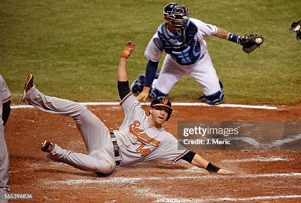 Designated hitter Nolan Reimold of the Baltimore Orioles scores a run in the seventh inning as catcher Jose Lobaton of the Tampa Bay Rays missed the...