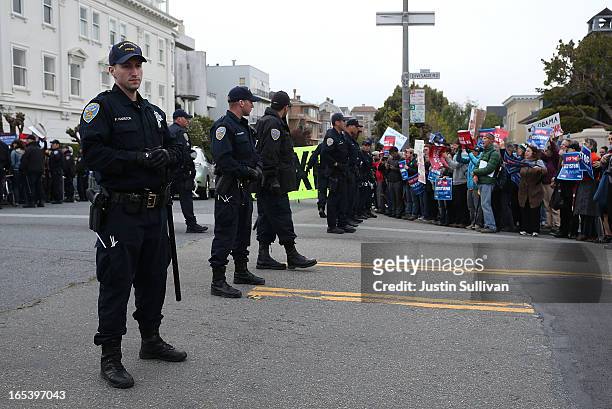 San Francisco police officers stand watch as demonstrators protest near the site of a fundraiser on April 3, 2013 in San Francisco, California....