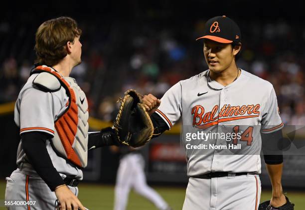 Shintaro Fujinami of the Baltimore Orioles celebrates with Adley Rutschman at the end of the eighth inning against the Arizona Diamondbacks at Chase...