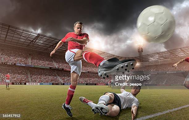 come up soccer player kicking football - tackling stockfoto's en -beelden