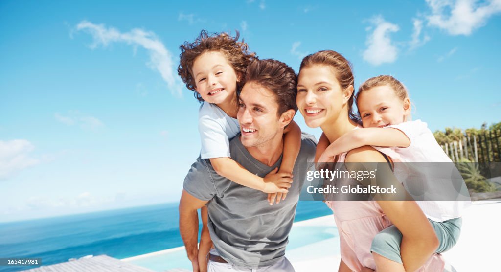 Children riding piggyback with parents at a beach