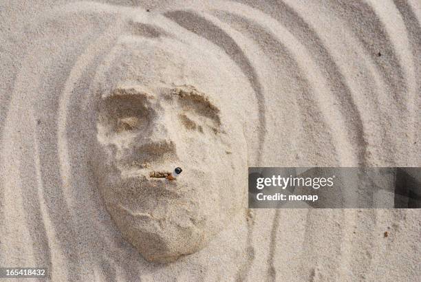 smoking face in the sand - sand sculpture stock pictures, royalty-free photos & images