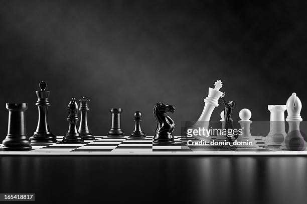 businessman in suit supporting falling white chess king, chess board - king chess piece stock pictures, royalty-free photos & images