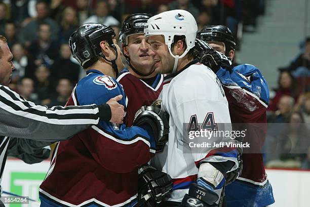 Defenseman Todd Bertuzzi of the Vancouver Canucks mixes it up with right wing Dan Hinote and defenseman Adam Foote of the Colorado Avalanche during...