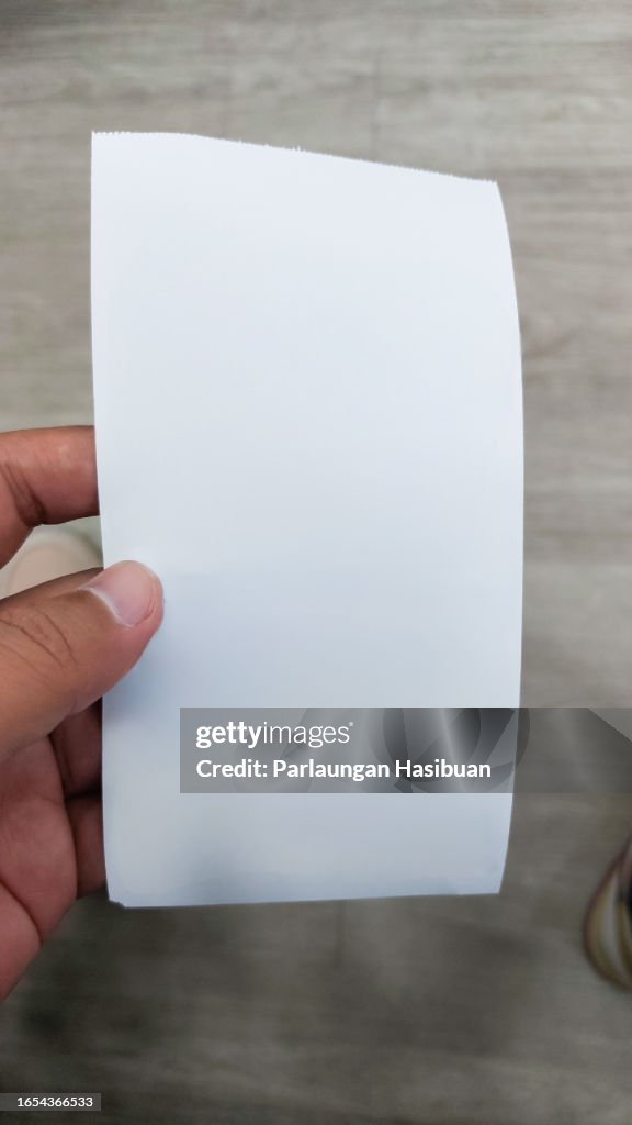 Hand holding blank shopping receipt
