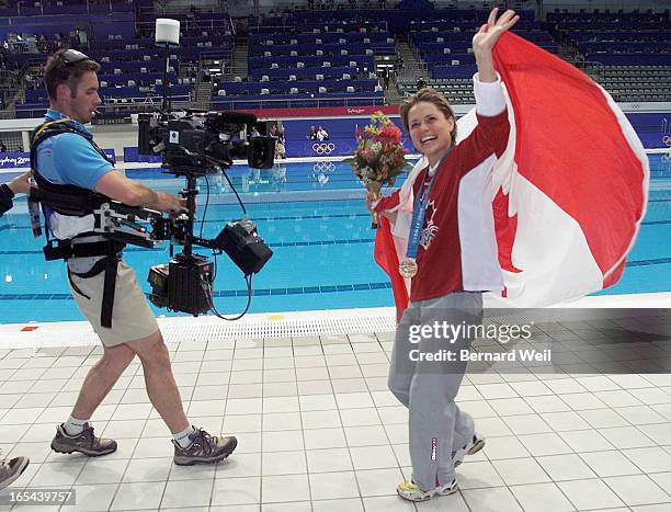 Canadian Olympic diver Anne Montminy parades her bronze medal in women's 10M platform diving for fans along poolside after the podium ceremonies,...