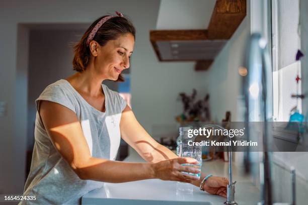 beautiful woman filling a glass with filtered water right from the tap - 水喉水 個照片及圖片檔