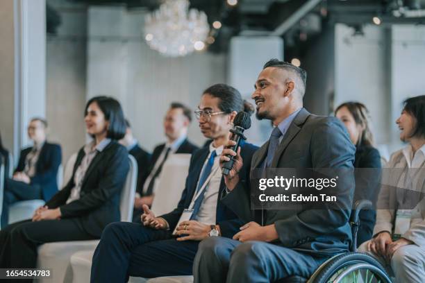 disable asian indian entrepreneur in wheelchair asking question at business conference among participants in workshop - business conference stock pictures, royalty-free photos & images