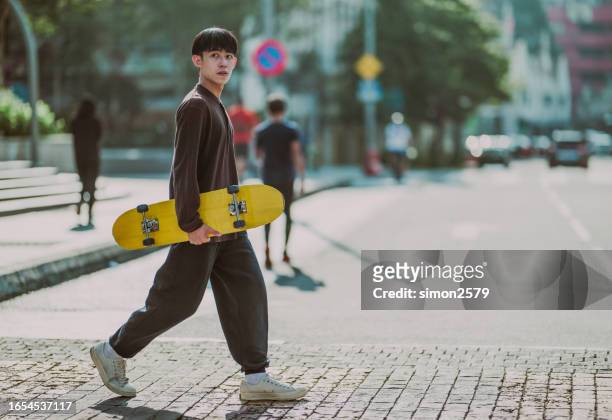 skateboarding through the city: a young asian commuter - man skating stock pictures, royalty-free photos & images