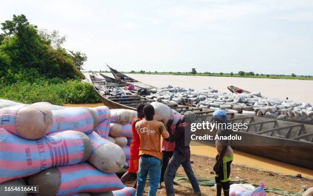 People unload the cargos from boats came from Benin, on the banks of the Niger River to be transported on trucks and then travel to different cities...