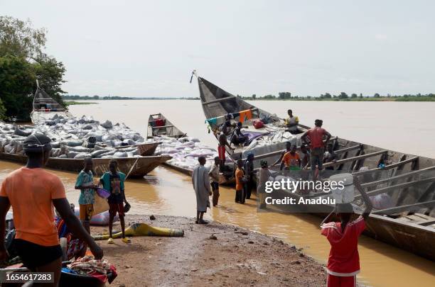 People unload the cargos from boats came from Benin, on the banks of the Niger River to be transported on trucks and then travel to different cities...