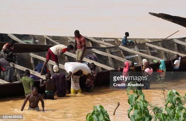 People unload the cargos from boats came from Benin, on the banks of the Niger River to be transported on trucks and then travel to different cities...