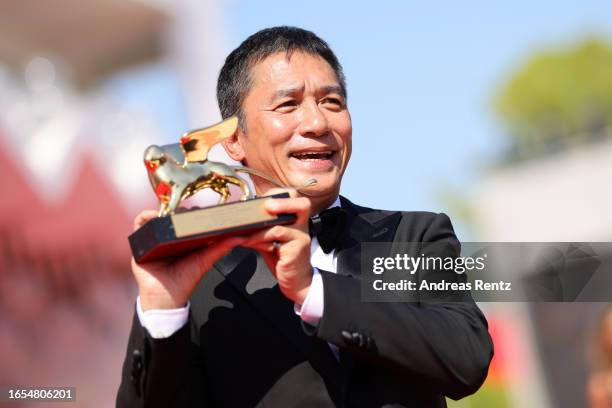 Tony Leung Chiu-Wai poses with the award on the red carpet during the Golden Lion For Lifetime Achievement Award Ceremony at the 80th Venice...