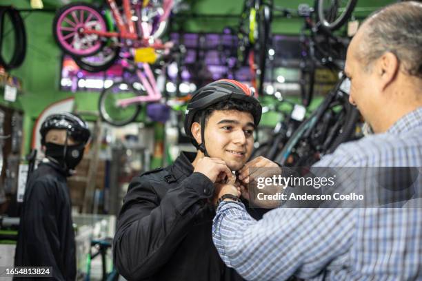 father and son putting on a cycling helmet - bike store stock pictures, royalty-free photos & images