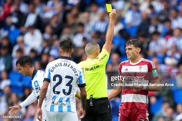 Match referee Javier Iglesias Villanueva shows a yellow card to Lucas Boye of Granada during the LaLiga EA Sports match between Real Sociedad and...