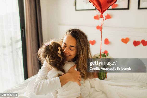 little daughter wakes up mother and giving gifts for her in bed. - homemade valentine stock pictures, royalty-free photos & images