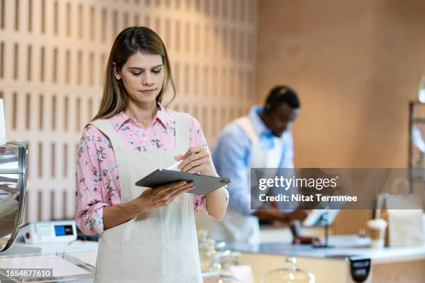 maximize your restaurant’s efficiency with pos system integration to improve customer experience and drive growth. shot of a female cafe owner using a tablet computer in front of a cafe counter to track order changes and new orders from customers. - compostable coffee stock pictures, royalty-free photos & images