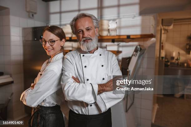 experienced baker and his female apprentice looking at camera - baker smelling bread stockfoto's en -beelden