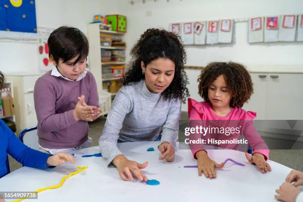 diverse group of students following their teacher working with plasticine during class at school - child care worker stock pictures, royalty-free photos & images