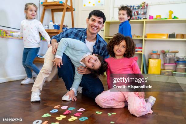 portrait of diverse group of kids and cheerful teacher learning numbers and smiling very playfully at the camera - child care worker stock pictures, royalty-free photos & images