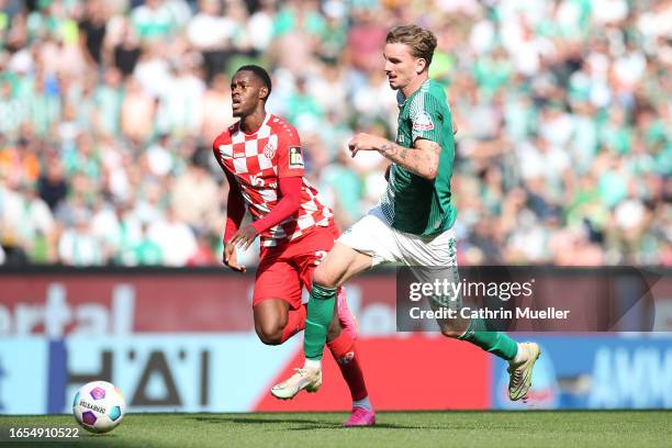 Edimilson Fernandes of 1.FSV Mainz 05 competes for the ball with Nick Woltemade of Werder Bremen during the Bundesliga match between SV Werder Bremen...