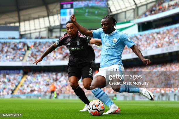 Jeremy Doku of Manchester City crosses the ball under pressure from Kenny Tete of Fulham during the Premier League match between Manchester City and...