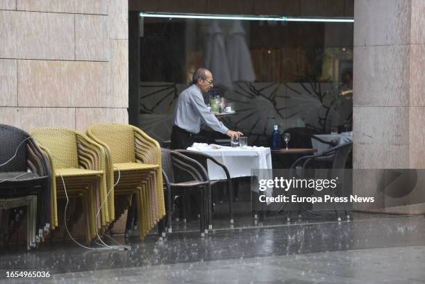 Waiter picks up a table on a terrace while it rains, on 02 September, 2023 in Huesca, Aragon, Spain. In several regions of Aragon and Navarra, where...