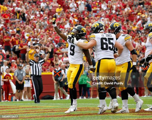 Running back Jaziun Patterson of the Iowa Hawkeyes celebrates with teammates offensive lineman Logan Jones, and defensive lineman Logan Lee of the...