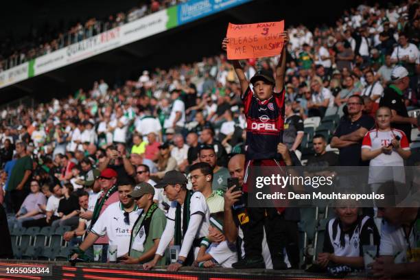 Young Bayern Munich fan holds a sign reading "Harry Kane please give me your shirt" prior to the Bundesliga match between Borussia Mönchengladbach...