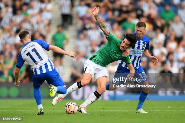Sandro Tonali of Newcastle United is challenged by Billy Gilmour and Pascal Gross of Brighton & Hove Albion during the Premier League match between...