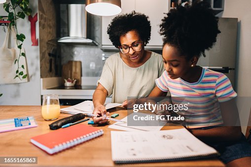 Mother helping her daughter with homework in the kitchen at apartment Mother helping her daughter with homework in the kitchen at apartment