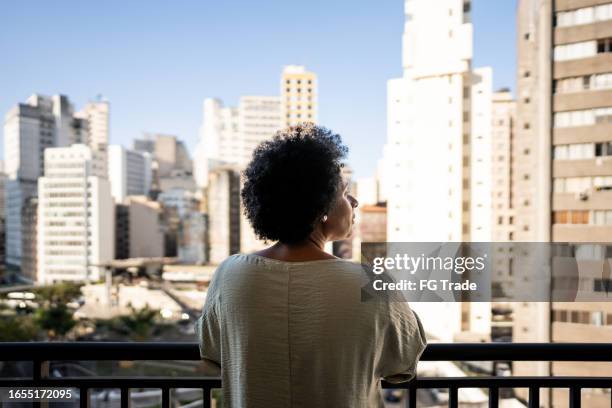 rear view of a mature woman contemplating on the balcony at apartment - brazil city stock pictures, royalty-free photos & images